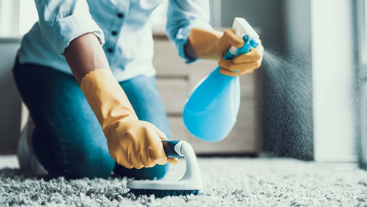 Person cleaning carpet with spray bottle and iron, professional cleaning service.